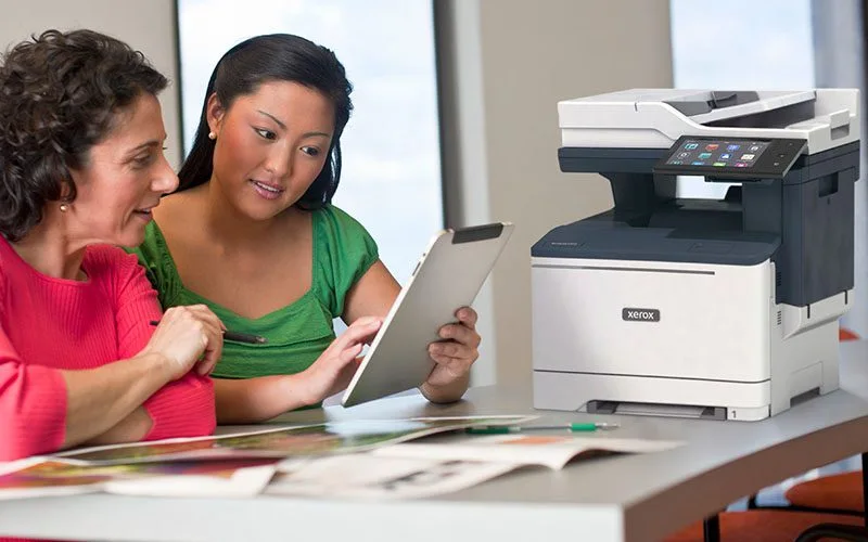 Deux femmes utilisant une tablette devant une imprimante multifonction Xerox® VersaLink® B415
