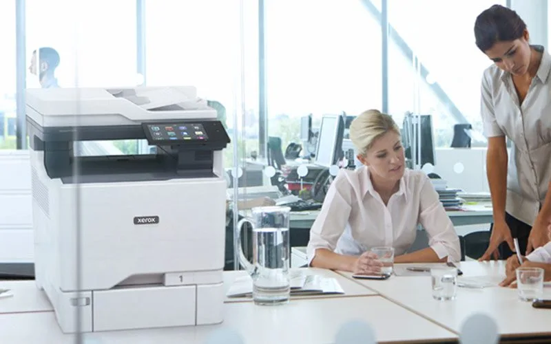 Deux femmes travaillant dans un bureau à côté d'une imprimante couleur multifonctions Xerox® VersaLink® C625