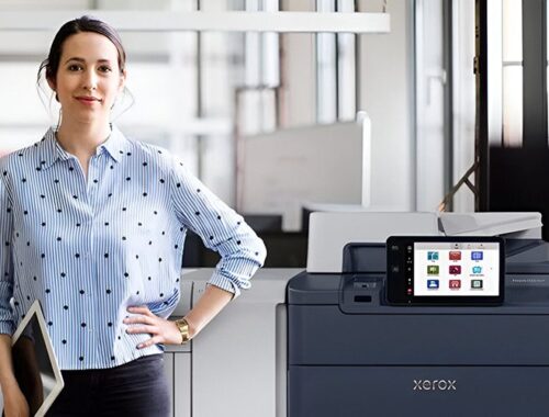 Une femme se tenant à côté de l'imprimante Xerox® PrimeLink® Série C9200 dans un environnement de bureau moderne